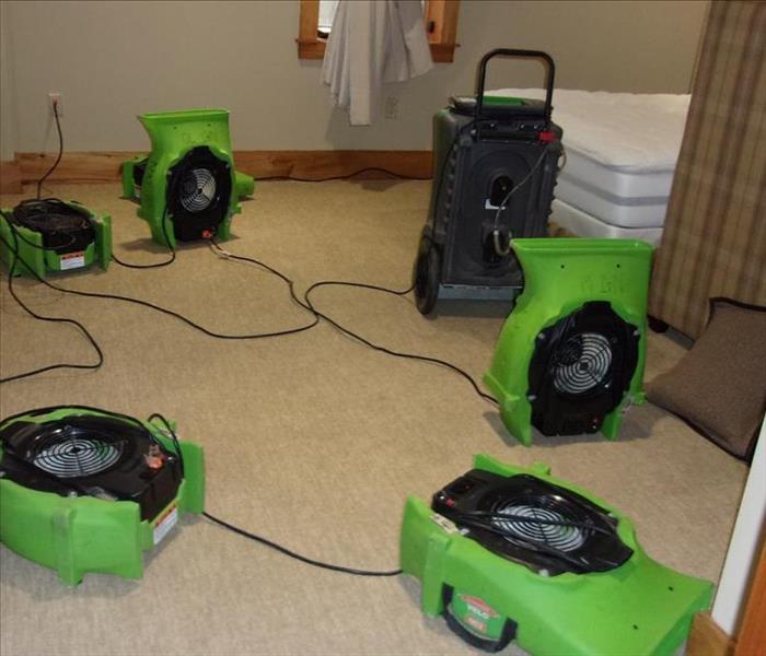 Air movers and dehumidifiers drying water damaged carpet