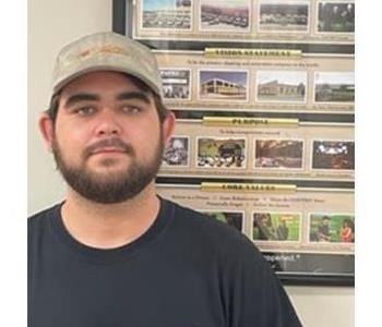 Man with beard standing in front of framed picture 