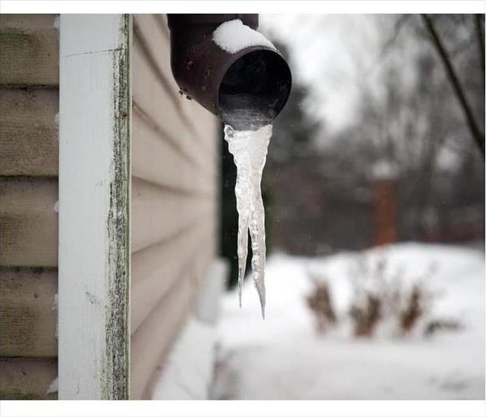 Frozen water coming out of a drain pipe at a residential home
